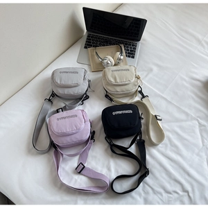 Flat lay of small nylon crossbody bags in grey, beige, purple, and black with wide straps