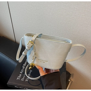 Detail of light blue croc-effect bucket bag with gold heart pendant and brand logo