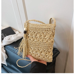 Detail of straw crossbody bag with floral crochet pattern and wooden bead tassels