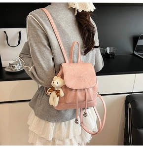 Detailed shot of a pink pleated bucket backpack with cute white bear charm accessory