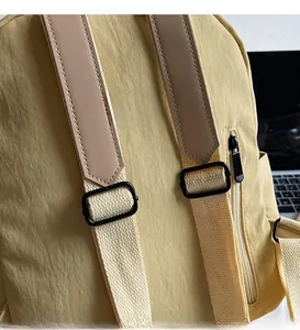 Detail of adjustable nylon shoulder straps with leather reinforcement on a yellow backpack