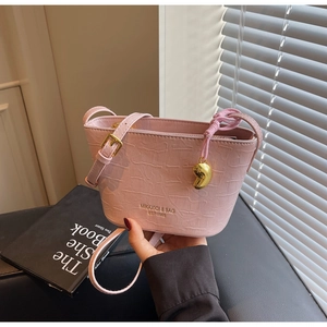 Detail view of pink crocodile embossed bucket bag with gold lettering and charm