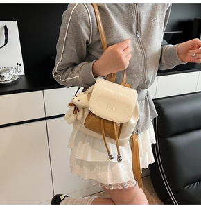 Detail of two-tone leather bucket backpack with bear plush charm and metal drawstring
