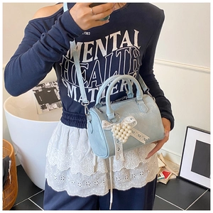 Detail of light blue Boston bag featuring pearl heart pendant and white lace bow decoration