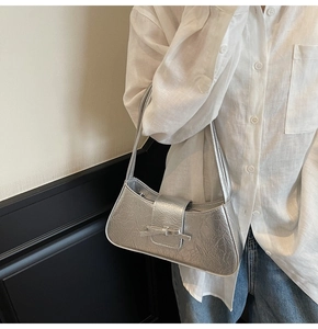 Detail of silver metallic underarm bag with pleated texture and stylish bow decoration