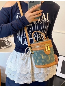 Chic blue denim monogram bucket bag with brown leather trim and golden metal hardware details