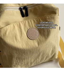 Detail of waterproof yellow nylon backpack fabric with circular logo and dual zippers