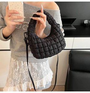 Detail of black quilted cloud bag with plush texture and detachable shoulder strap