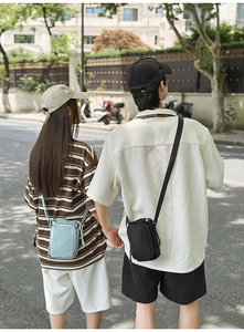 Outdoor street view of a small nylon crossbody phone bag with an adjustable strap