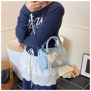 Light blue cylinder handbag with lace bow and pearl heart charm shown on model