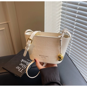 Detail of white crocodile pattern bucket bag with gold heart charm and logo