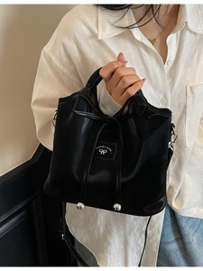 Elegant black glossy bucket bag with drawstring bow and silver metal details