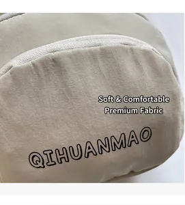 Detail of beige textured fabric bag featuring black QIHUANMAO logo and smooth zipper