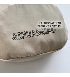 Detail showing high-quality canvas texture and printed QIHUANMAO logo on the beige bag