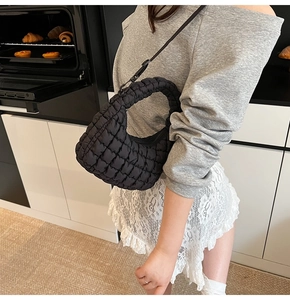 Close-up of black quilted cloud bag with pleated texture and adjustable shoulder strap