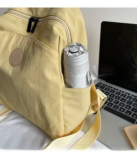Detail of the side pocket on a yellow nylon backpack holding a grey folded umbrella