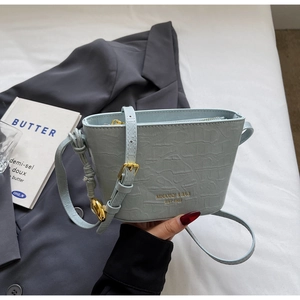 Close-up of light blue croc-embossed bucket bag with gold logo and hardware details
