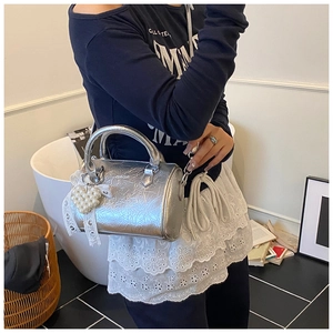 Detail of silver metallic cylinder bag with pearl heart pendant and lace ribbon texture