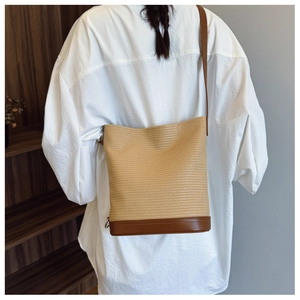 Detail showing woven texture and brown leather base of a bucket shoulder bag