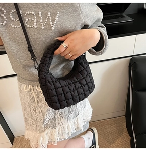 Close-up of a black quilted dumpling bag featuring a soft puffy texture and crossbody strap