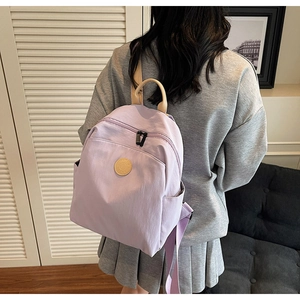 Detailed back view of a lavender nylon backpack on model showing adjustable beige straps