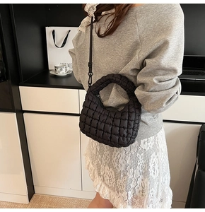 Detail of black quilted puffer bag showing nylon texture and adjustable shoulder strap