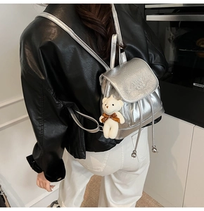 Detail of silver metallic mini backpack with Enjoy Every Day embossing and bear charm