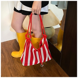 Detail view of a striped mesh tote bag with red shoulder strap and metal ring hardware