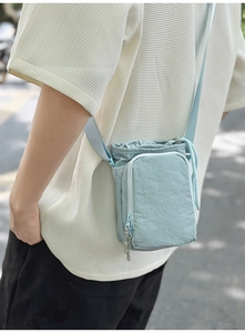 Detail of light blue nylon phone bag with drawstring and adjustable strap
