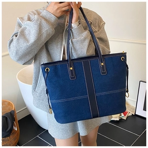 Detail of denim tote bag with contrast stitching and reinforced metallic studs