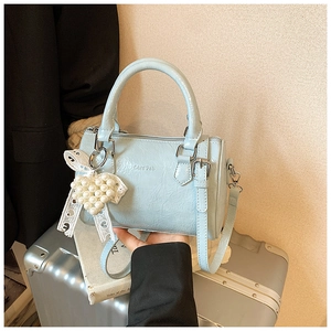 Détail du sac Boston en cuir verni bleu clair avec breloque cœur en perles et dentelle