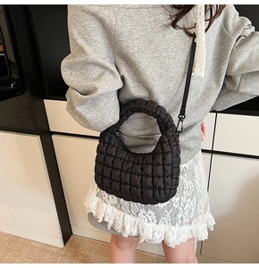 Detail of black quilted cloud bag with textured fabric and adjustable crossbody strap