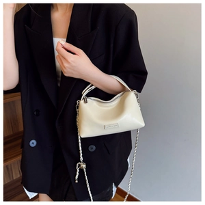 Close-up of beige moon-shaped PU leather bag with silver logo and metal chain strap