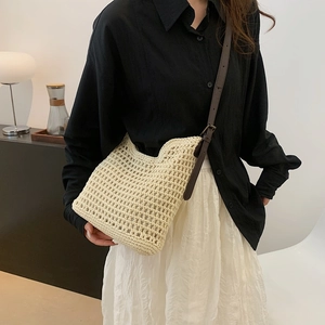 Detailed shot of beige woven tote bag with hollow grid texture and brown leather strap