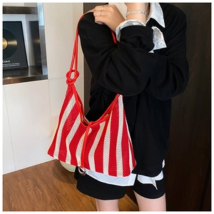 Detail of red and white striped mesh tote bag with knot strap and metal ring accent