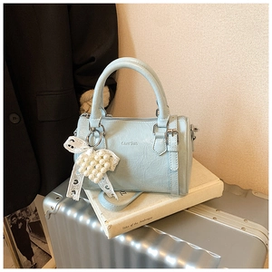 Détail du mini sac Boston bleu clair avec breloque nœud en perles et finitions argentées