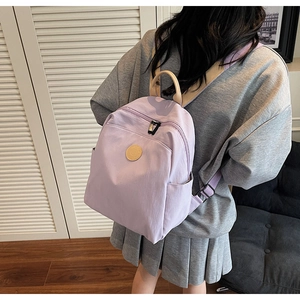 Detailed view of light purple nylon backpack with adjustable straps worn by a model