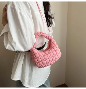 Pink quilted cloud bag with puffy texture and silver zipper shown on a model side view