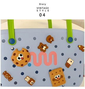 Close-up of blue EVA tote bag with green handles and cute cartoon character charms