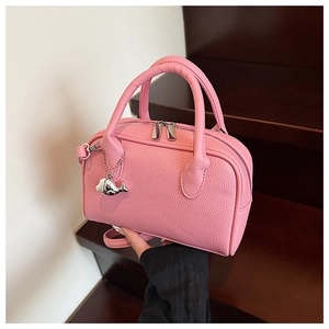 Detailed macro view of pink litchi grain leather bag with a silver whale charm
