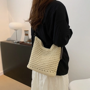 Detail view of a beige crochet tote bag with large mesh pattern and brown straps