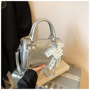 Détail du sac Boston argenté avec breloque cœur en perles et cuir métallisé à effet froissé