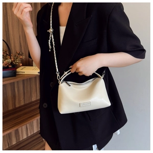Close-up of cream crossbody bag featuring matte leather texture and gold metal chain strap