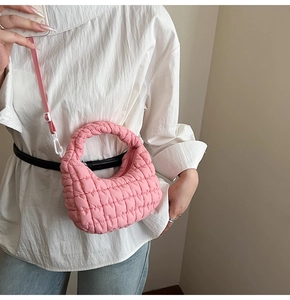 Detail of pink quilted cloud bag with puffy texture and adjustable shoulder strap