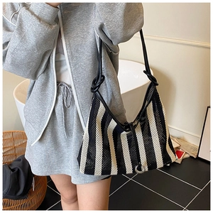 Detail of black and white striped mesh tote bag with knot strap and metal ring buckle