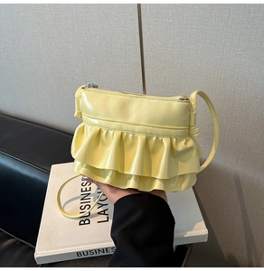 Detail of light yellow crossbody bag featuring elegant double-layered ruffle design