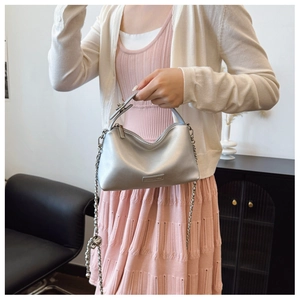 Silver metallic crossbody bag detail with chain strap on a model wearing pink dress
