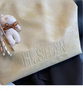 Detail of beige tote bag with leopard embossed texture and plush bunny charm