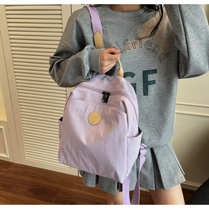 Detail shot of light purple fabric backpack with round logo patch and durable zipper pocket