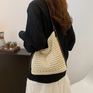 Detail of cream crochet knit shoulder bag with brown leather strap worn by a model